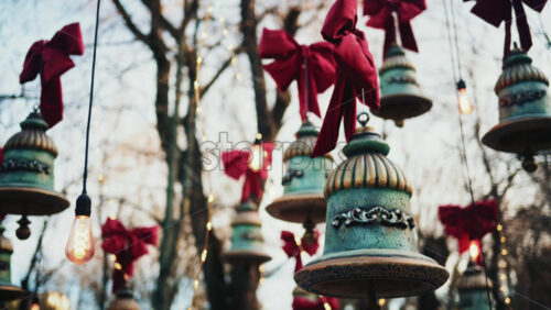 Video - Decorative hanging bells with red bows and warm string lights outdoors