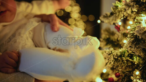 Video – Baby being held close to a decorated Christmas tree, reaching toward illuminated ornaments and lights - Starpik Stock