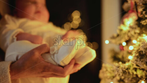 Video – Baby being held close to a decorated Christmas tree, reaching toward illuminated ornaments and lights - Starpik Stock
