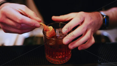 Video – Bartender adds an orange peel garnish to a freshly mixed cocktail - Starpik Stock