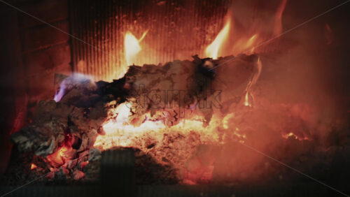 Video – Burning firewood inside a fireplace with glowing embers and warm flames - Starpik Stock