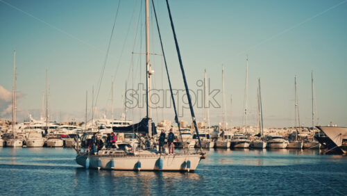 Video – Cannes, France – December 12, 2025: Sailboat moving through a marina with several people standing on deck during daylight - Starpik Stock