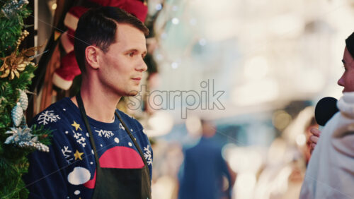 Video – Cannes, France – December 20, 2025: Man being interviewed on camera at a festive Christmas market decorated with lights and garlands - Starpik Stock