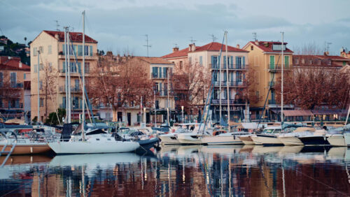 Video – Cannes, France – December 23, 2025: Boats lined up along a waterfront with colorful residential buildings behind them - Starpik Stock