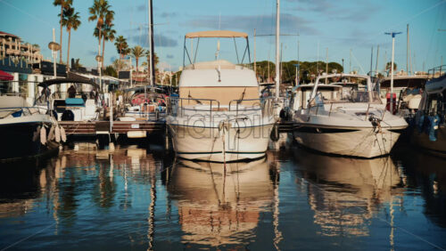 Video – Cannes, France – December 23, 2025: Front view of motorboats tied to a dock, with palm trees, waterfront buildings, and reflections creating a relaxed coastal atmosphere - Starpik Stock