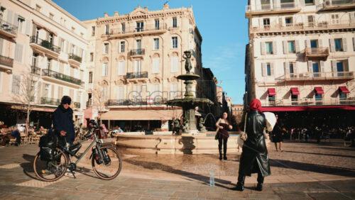 Video – Cannes, France – December 23, 2025: People gathering around a historic fountain in a sunlit city square - Starpik Stock