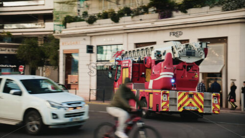 Video – Cannes, France – December 23, 2025: Red fire truck driving along La Croisette with palm trees and pedestrians in the background - Starpik Stock