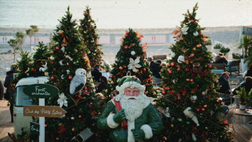 Video – Cannes, France – December 23, 2025: Santa Claus statue placed among decorated Christmas trees at a seaside holiday market - Starpik Stock
