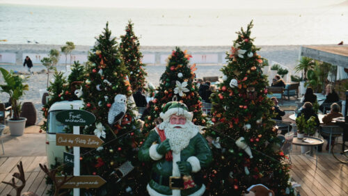 Video – Cannes, France – December 23, 2025: Santa Claus statue placed among decorated Christmas trees at a seaside holiday market - Starpik Stock