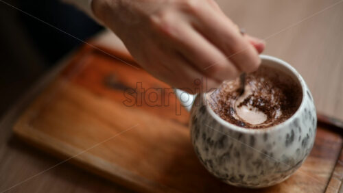 Video – Close up of a ceramic cup filled with hot chocolate topped with cocoa powder, placed on a wooden tray - Starpik Stock