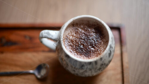 Video – Close up of a ceramic cup filled with hot chocolate topped with cocoa powder, placed on a wooden tray - Starpik Stock
