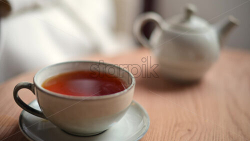 Video – Close up of a ceramic cup filled with hot tea placed on a matching saucer on a wooden table - Starpik Stock
