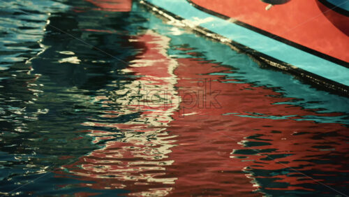 Video – Close up of colorful reflections from a boat hull rippling across the water surface - Starpik Stock