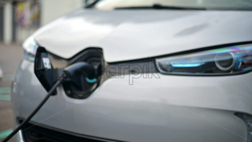 Video – Close up view of an electric vehicle charging cable connected to a white car - Starpik Stock