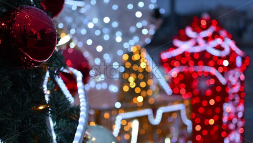 Video – Decorated Christmas tree ornaments in focus with illuminated festive installations blurred in the background - Starpik Stock