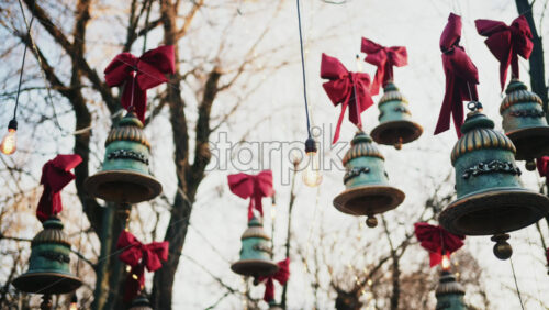 Video – Decorative hanging bells with red bows and warm string lights outdoors - Starpik Stock