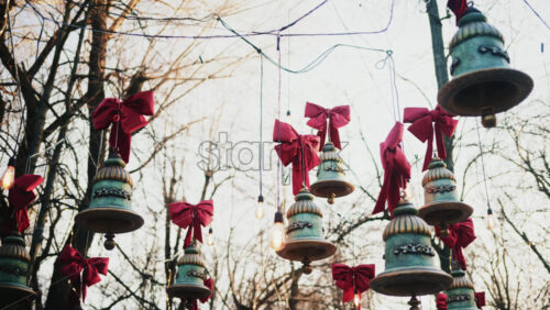 Video – Decorative hanging bells with red bows and warm string lights outdoors - Starpik Stock