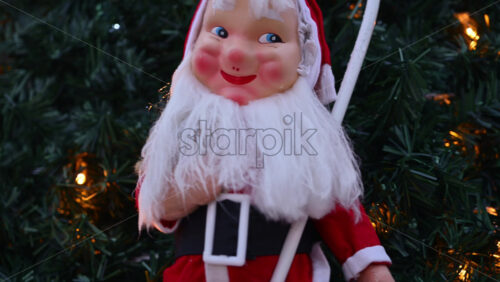Video – Festive Santa Claus decoration displayed outdoors, framed by Christmas tree branches and warm holiday lights - Starpik Stock
