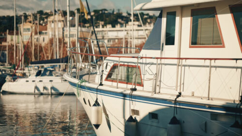 Video – Golfe Juan, France – December 15, 2025: Motor yacht moored at a marina with urban buildings and sailboats in the background - Starpik Stock