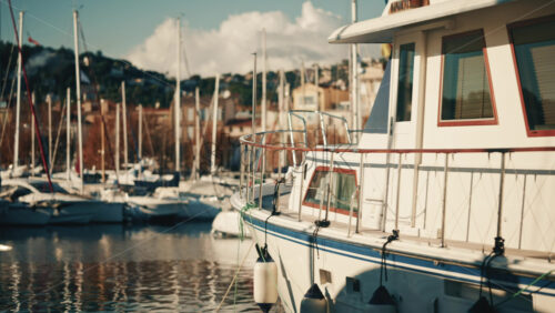 Video – Golfe Juan, France – December 15, 2025: Motor yacht moored at a marina with urban buildings and sailboats in the background - Starpik Stock