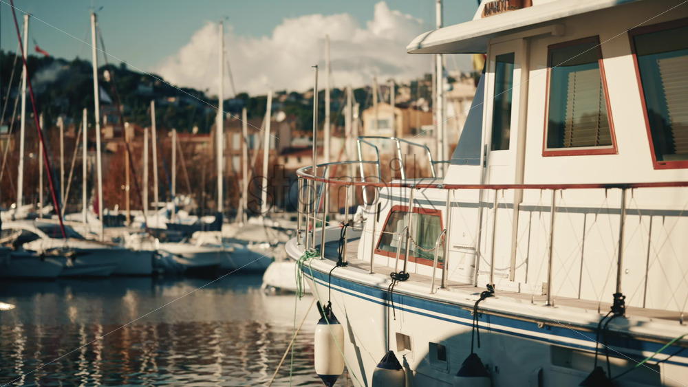 Video – Golfe Juan, France – December 15, 2025: Motor yacht moored at a marina with urban buildings and sailboats in the background - Starpik Stock