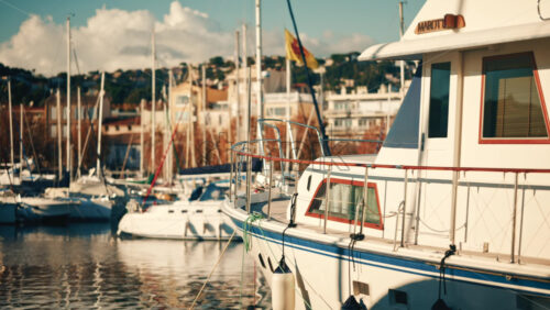Video – Golfe Juan, France – December 15, 2025: Motor yacht moored at a marina with urban buildings and sailboats in the background - Starpik Stock