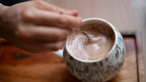 Video – Hand stirring hot chocolate inside a ceramic mug, creating creamy foam - Starpik Stock