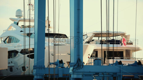 Video – Large white yachts positioned inside a blue metal lifting structure at a marina or shipyard - Starpik Stock