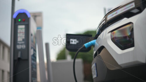 Video – White, electric vehicle parked at a public charging station in an urban environment - Starpik Stock