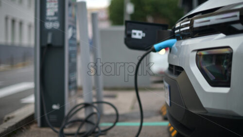 Video – White, electric vehicle parked at a public charging station in an urban environment - Starpik Stock