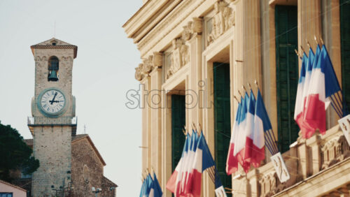Video – Wide shot of a historic building decorated with French tricolor flags under clear daylight - Starpik Stock