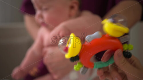 Infant lying face down across a caregiver's forearm, supported securely