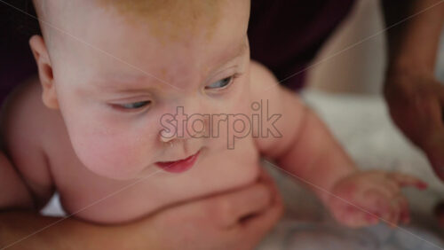 Infant raising head while supported on tummy, strengthening neck muscles during early development
