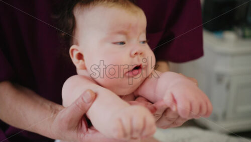 Infant raising head while supported on tummy, strengthening neck muscles during early development