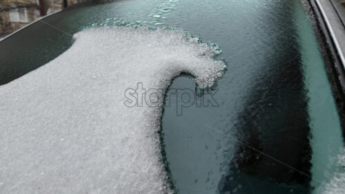 Partially melted ice on a car windshield forming an irregular transparent patch