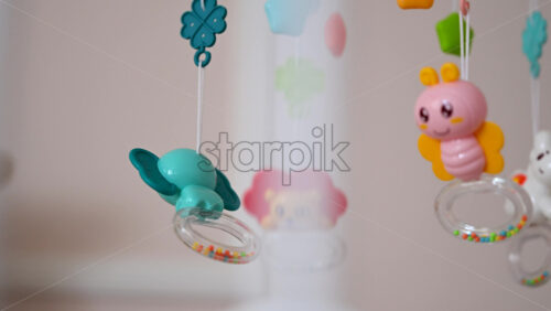 Close up of a hanging baby crib mobile with colorful animal toys gently swaying
