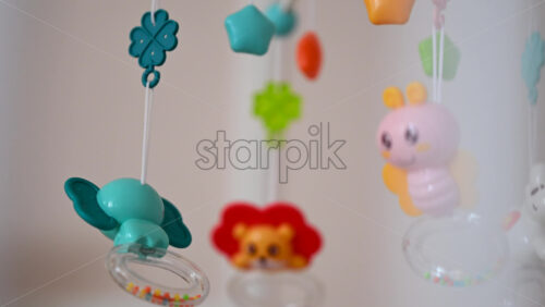 Close up of a hanging baby crib mobile with colorful animal toys gently swaying