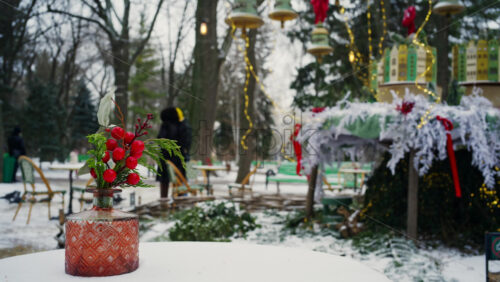 Festive winter decoration with red berries displayed on a table in an outdoor park cafe