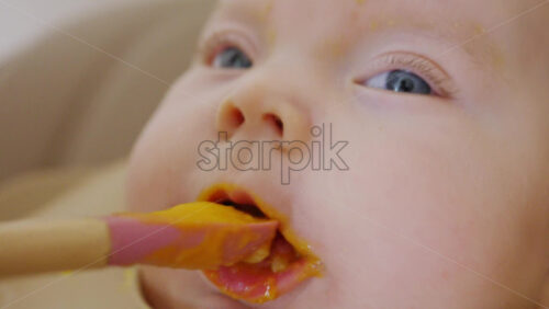 Close up of a baby being fed with a spoon, showing facial details and soft expressions