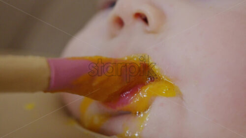 Close up of a baby being fed with a spoon, showing facial details and soft expressions