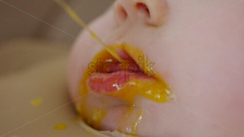 Close up of a baby being fed with a spoon, showing facial details and soft expressions
