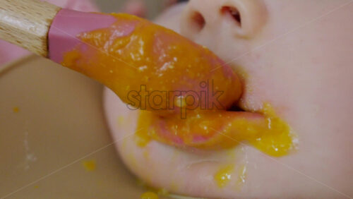 Close up of a baby being fed with a spoon, showing facial details and soft expressions