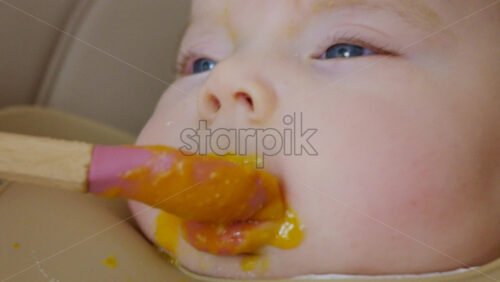 Close up of a baby being fed with a spoon, showing facial details and soft expressions