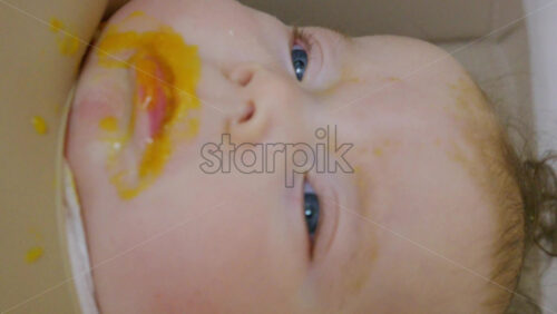 Close up of a baby being fed with a spoon, showing facial details and soft expressions. Vertical