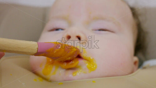 Close up of a baby being fed with a spoon, showing facial details and soft expressions
