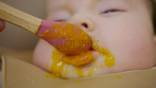 Close up of a baby being fed with a spoon, showing facial details and soft expressions