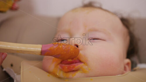 Close up of a baby being fed with a spoon, showing facial details and soft expressions