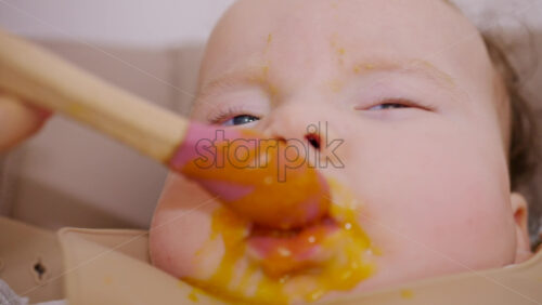 Close up of a baby being fed with a spoon, showing facial details and soft expressions