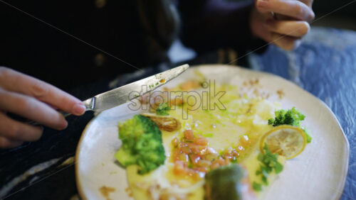 Close up of a fork lifting broccoli from a plate with salmon and vegetables
