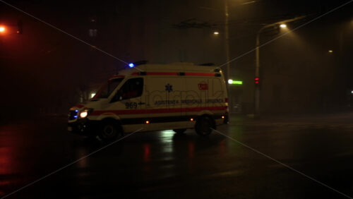 Chisinau, Moldova - January 11, 2026: Ambulance driving through a foggy city street at night with headlights and emergency lights on